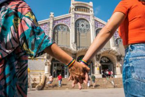 Pareja paseando de la mano frente al Mercado de Colón de València, uno de los destinos de la Red Española de Destinos por la Diversidad.